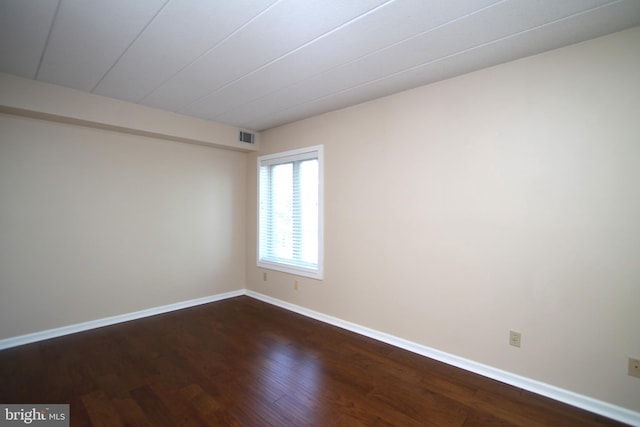 spare room with visible vents, dark wood-style flooring, and baseboards