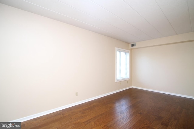 spare room with baseboards, dark wood finished floors, and visible vents