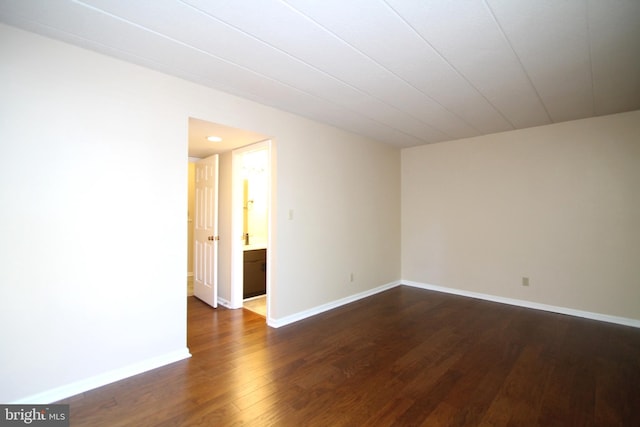 unfurnished room with dark wood-style flooring and baseboards