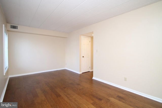 unfurnished room featuring baseboards, dark wood-style floors, and visible vents
