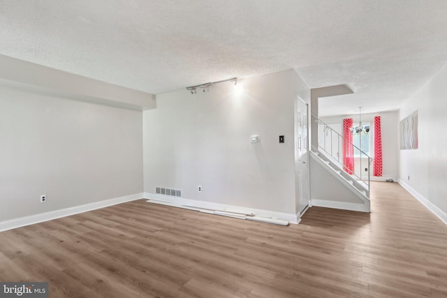 4927 Oxford Ct, Bensalem, PA 19020 - unfurnished living room with a textured ceiling, visible vents, wood finished floors, baseboards, and a chandelier