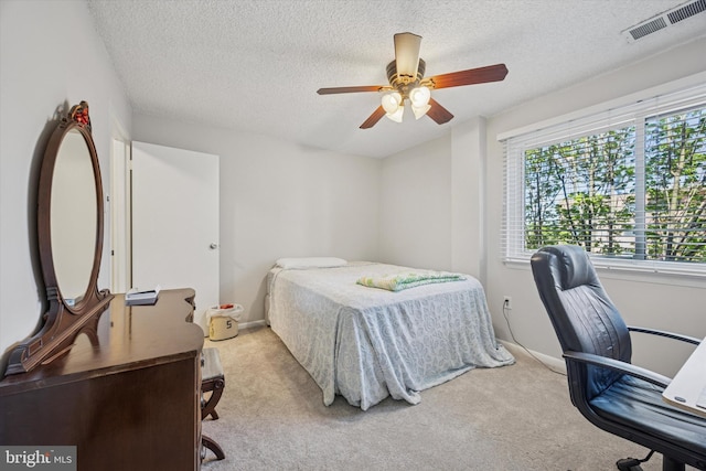 carpeted bedroom featuring baseboards, a textured ceiling, visible vents, and ceiling fan