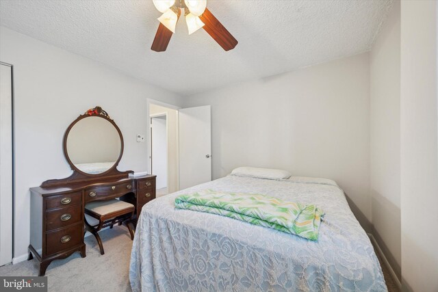 carpeted bedroom featuring baseboards, ceiling fan, and a textured ceiling