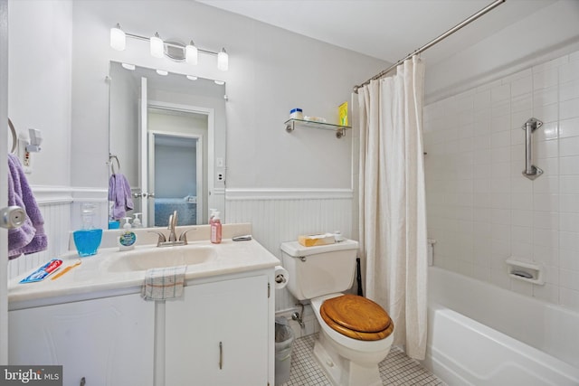 bathroom featuring tile patterned flooring, shower / tub combo with curtain, vanity, toilet, and a wainscoted wall