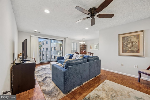 living area featuring a textured ceiling, visible vents, baseboards, ceiling fan with notable chandelier, and recessed lighting