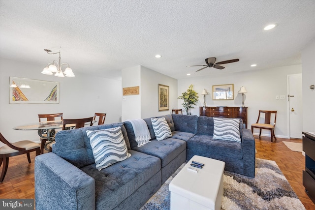 living room featuring ceiling fan with notable chandelier, recessed lighting, and a textured ceiling