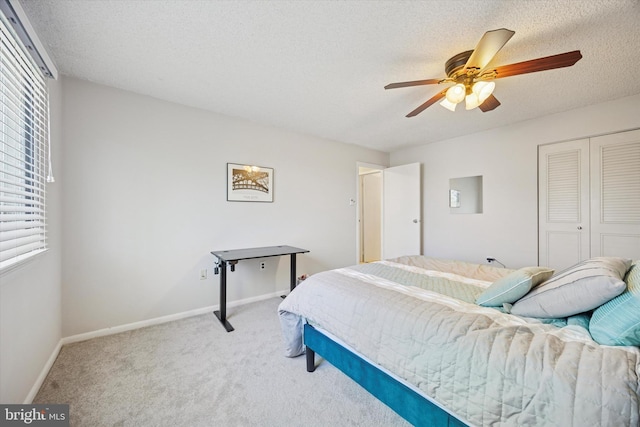 carpeted bedroom featuring baseboards, ceiling fan, a closet, and a textured ceiling
