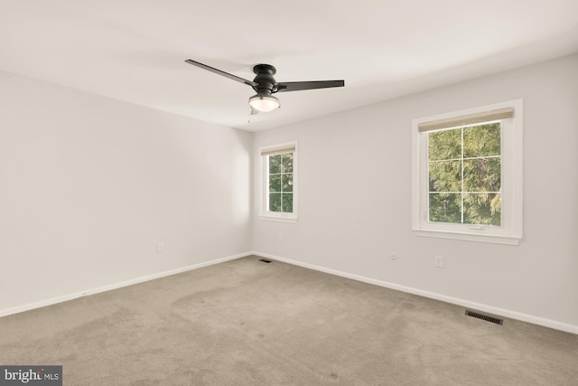 carpeted spare room featuring a ceiling fan, baseboards, visible vents, and a wealth of natural light