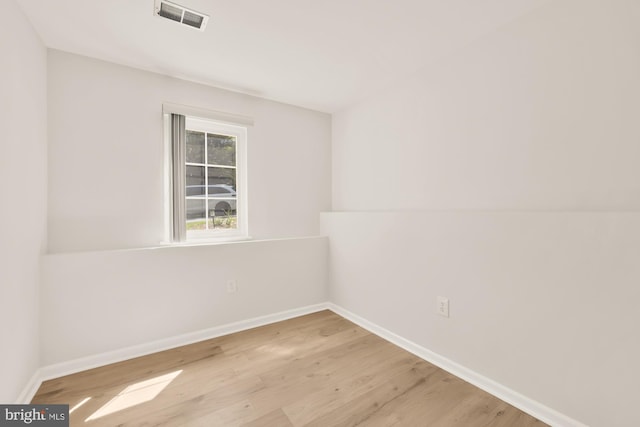 empty room with baseboards, wood finished floors, and visible vents