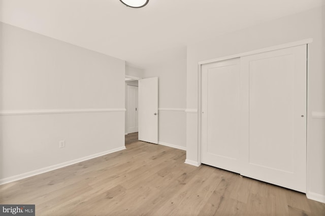 unfurnished bedroom featuring a closet, baseboards, and wood finished floors