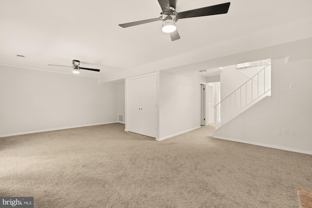 carpeted spare room featuring a ceiling fan, baseboards, visible vents, and stairway