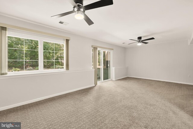 carpeted spare room with visible vents, a ceiling fan, and baseboards