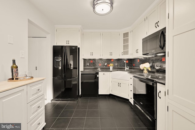 kitchen with white cabinets, backsplash, dark tile patterned floors, glass insert cabinets, and black appliances