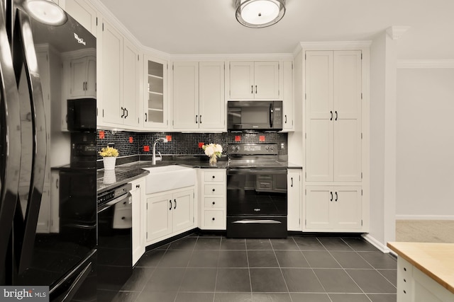 kitchen with dark tile patterned floors, white cabinetry, black appliances, and tasteful backsplash