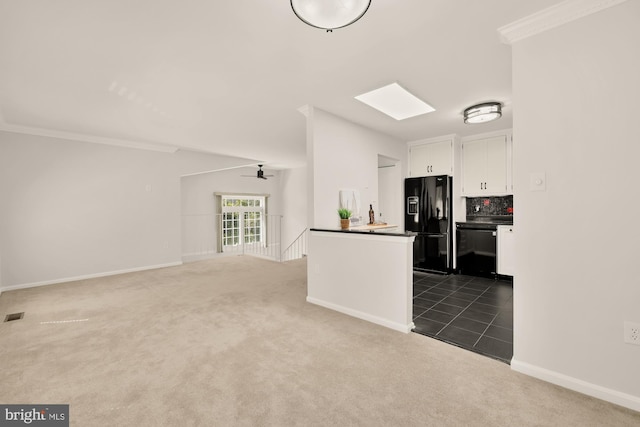 kitchen featuring crown molding, dark countertops, dark colored carpet, white cabinets, and black appliances