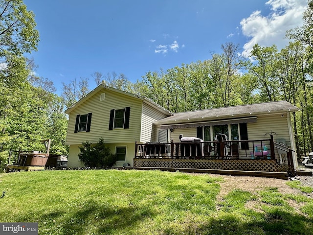 back of property with a hot tub, a deck, and a yard