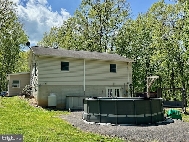 back of house with a lawn, an outdoor pool, and french doors