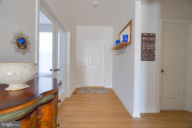 corridor featuring baseboards and light wood-style flooring