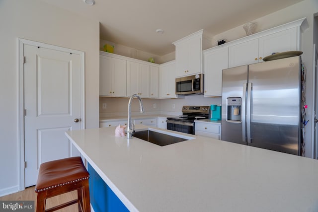 kitchen with white cabinets, appliances with stainless steel finishes, a sink, and light countertops