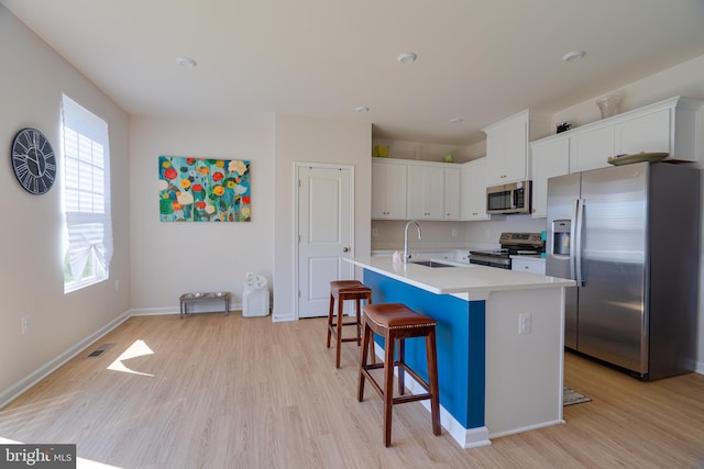 kitchen with a sink, stainless steel appliances, light wood finished floors, and visible vents