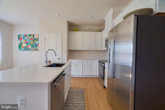 kitchen with white cabinets, a sink, light wood finished floors, light countertops, and stainless steel appliances