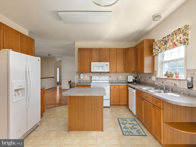 kitchen with white appliances, decorative backsplash, a sink, and a center island