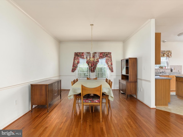 dining space featuring light wood-style floors, a healthy amount of sunlight, crown molding, and a chandelier