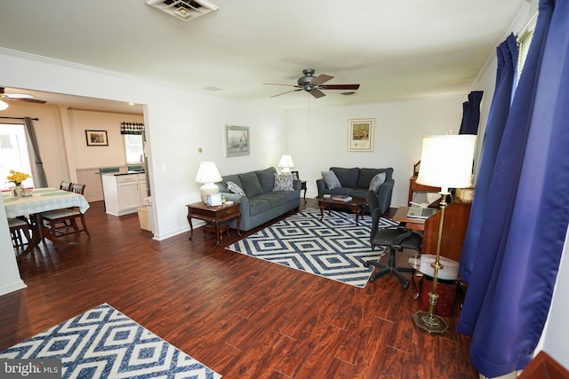 living area featuring visible vents, crown molding, ceiling fan, and wood finished floors