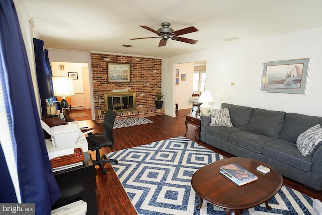 living area with crown molding, ceiling fan, a brick fireplace, wood finished floors, and visible vents