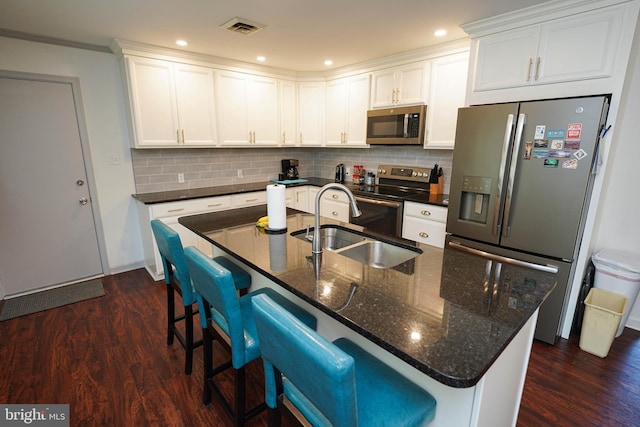 kitchen with appliances with stainless steel finishes, a sink, visible vents, and dark wood-type flooring