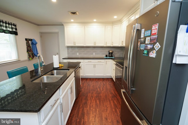 kitchen with appliances with stainless steel finishes, tasteful backsplash, a sink, dark wood-style floors, and white cabinetry