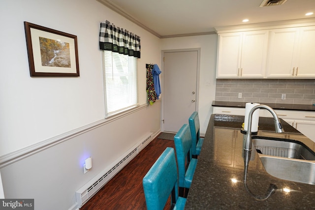 kitchen featuring a sink, ornamental molding, baseboard heating, and white cabinetry