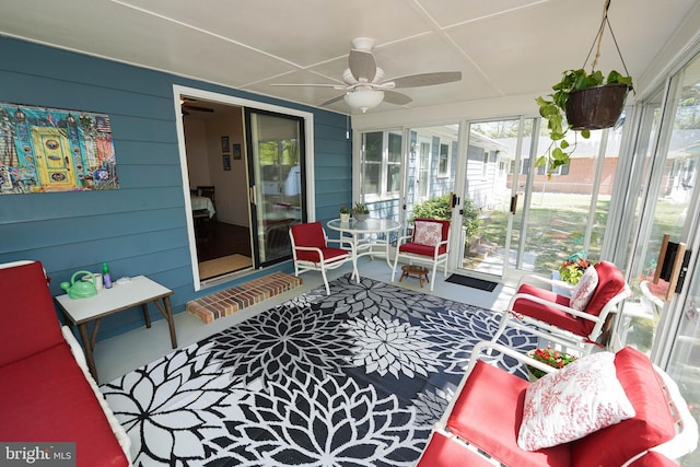 sunroom featuring a ceiling fan and wood walls