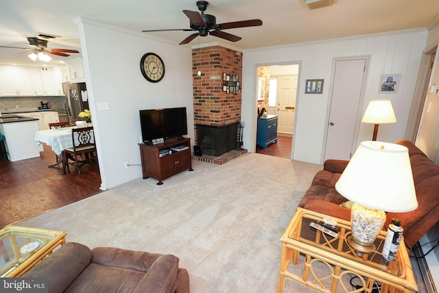 living area with crown molding, visible vents, a fireplace, dark wood-type flooring, and a ceiling fan