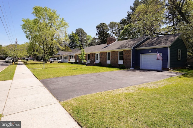 ranch-style home featuring aphalt driveway, a chimney, brick siding, a front lawn, and an attached garage
