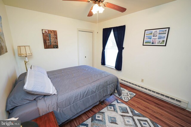 bedroom featuring ceiling fan, a baseboard radiator, a closet, and wood finished floors