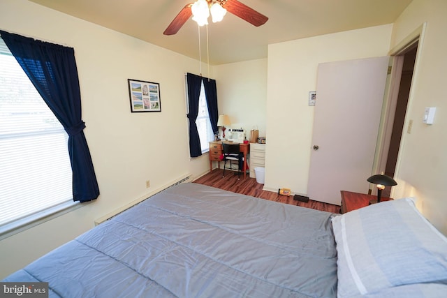 bedroom featuring ceiling fan, wood finished floors, baseboard heating, and multiple windows