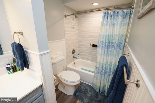 bathroom with wood finished floors, shower / bathtub combination with curtain, a wainscoted wall, and toilet