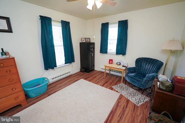 living area featuring a healthy amount of sunlight, a baseboard heating unit, and wood finished floors