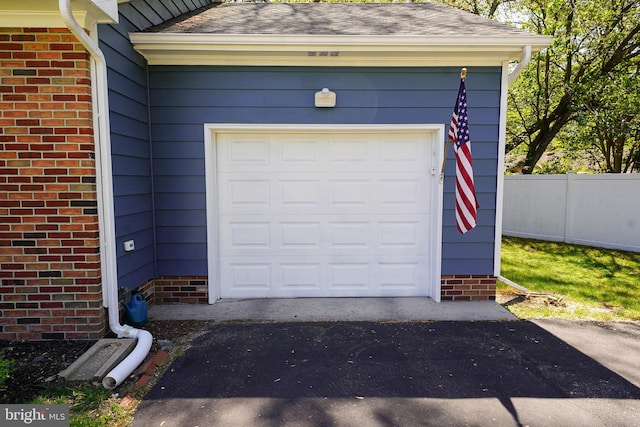 garage featuring fence and driveway