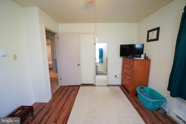 bedroom with baseboards, a baseboard radiator, connected bathroom, and dark wood-type flooring