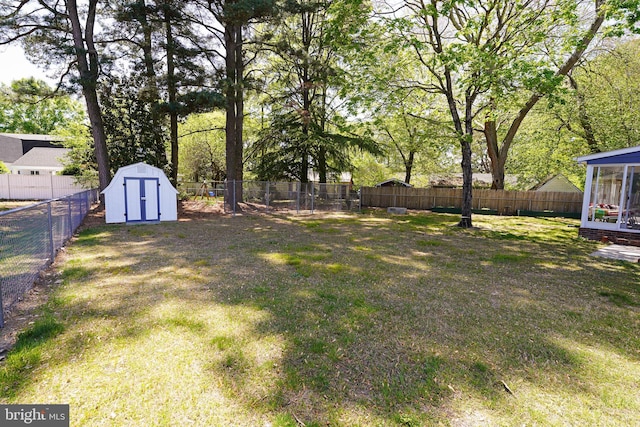 view of yard featuring a sunroom, a fenced backyard, an outbuilding, and a storage shed