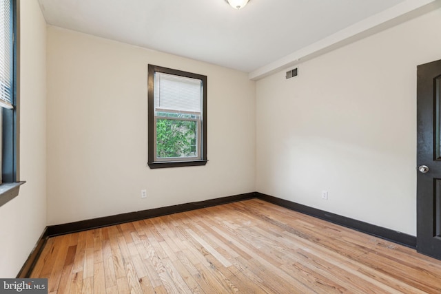 unfurnished room with visible vents, light wood-style flooring, and baseboards