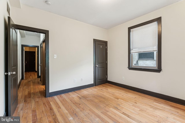 unfurnished room featuring light wood-style floors, visible vents, and baseboards
