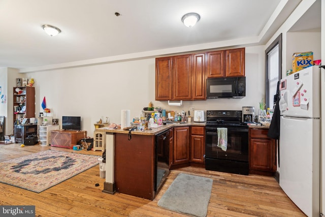 kitchen with black appliances, light wood finished floors, a peninsula, and open floor plan
