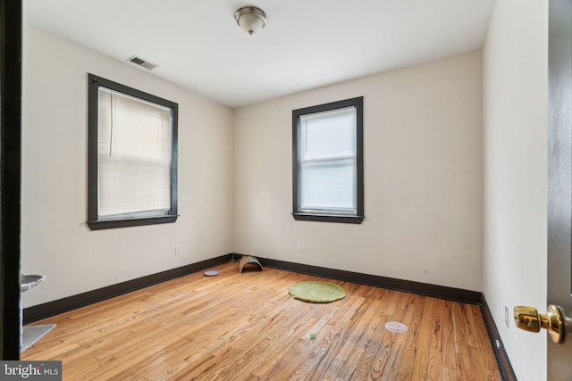 spare room featuring baseboards, visible vents, and wood finished floors
