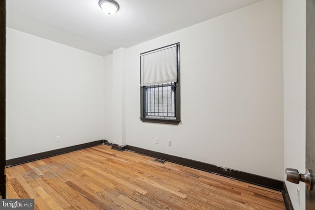 spare room featuring light wood finished floors, baseboards, and visible vents