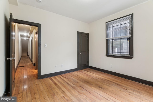 empty room featuring light wood-style floors, visible vents, and baseboards