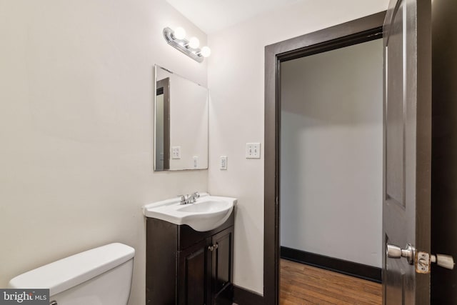 bathroom with toilet, vanity, and wood finished floors