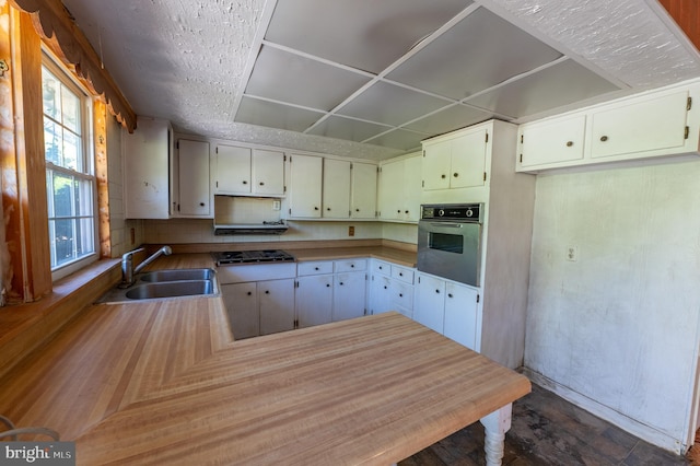 kitchen featuring gas cooktop, a sink, light countertops, a peninsula, and oven